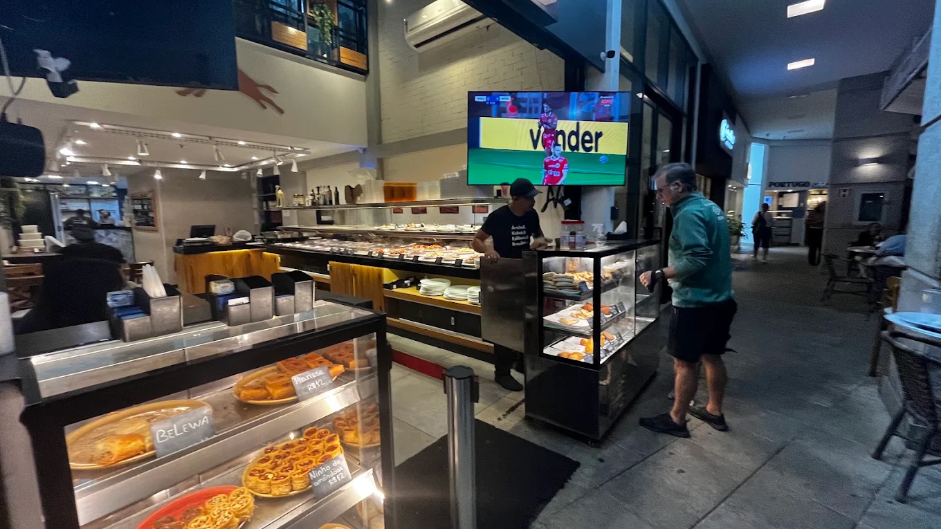 Televisão transmitindo jogo de futebol no salão do restaurante
